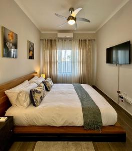 a bedroom with a large bed with a ceiling fan at d’Pinx Nest in Gaborone