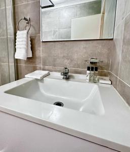 a white sink in a bathroom with a mirror at d’Pinx Nest in Gaborone