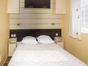 Saâcy-sur-MarneにあるCamping Nature et insolite proche Disneylandのベッドルーム1室(白い枕2つ付きのベッド1台付)
