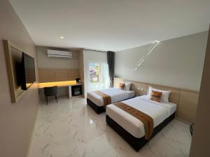 ein Hotelzimmer mit zwei Betten und einem Schreibtisch in der Unterkunft THE HUB SURATTHANl in Surat Thani