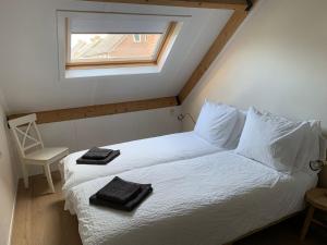 1 dormitorio con 1 cama con sábanas blancas y ventana en Studio 8, en Zoutelande