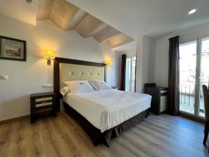 a bedroom with a large bed and a large window at Antídoto Rooms Zocodover in Toledo