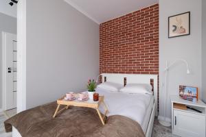 a bedroom with a brick wall and a bed with a table at Dąbska Studio with Terrace & Parking by Renters in Krakow