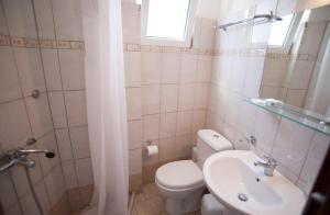 a bathroom with a white toilet and a sink at Giorgio Apartments in Nikiana