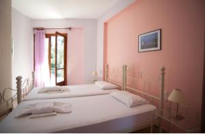 two beds in a bedroom with pink walls at Giorgio Apartments in Nikiana