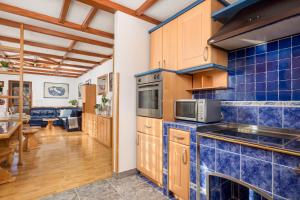 una cocina con paredes de azulejos azules y armarios de madera. en Holiday Home & Spa Kozji Vrh, en Čabar