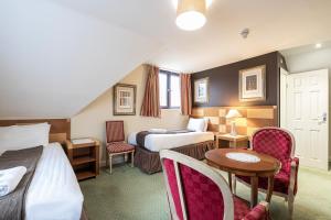 a hotel room with two beds and a table and chairs at Barrington Lodge in Crawley