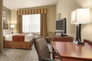 Habitación de hotel con cama y escritorio con TV. en Seffner Inn and Suites, en Seffner