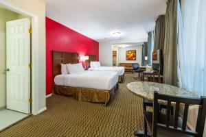 a hotel room with two beds and a red wall at Quality Inn & Suites in Vancouver