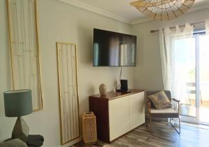 a living room with a dresser and a tv on the wall at Estrela do Mar in Gafanha da Nazaré