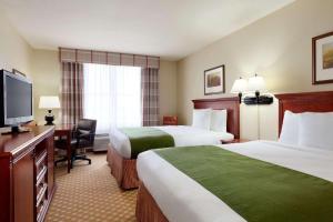 a hotel room with two beds and a flat screen tv at Country Inn & Suites by Radisson, Gillette, WY in Gillette