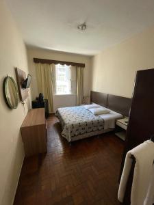a hotel room with a bed and a mirror at Brasil Palace Hotel in Belo Horizonte
