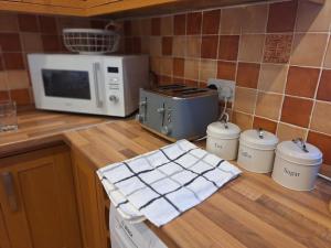 a kitchen with a counter top with a microwave at Uplands Grove Bungalow in Wolverhampton