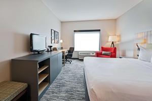 a hotel room with a bed and a flat screen tv at Country Inn & Suites by Radisson, Bloomington-Normal Airport, IL in Bloomington