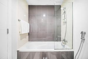 a bathroom with a tub and a glass shower at Aliving Luxury 3BR Villa With Maid Room Damac Hills 2 in Dubai