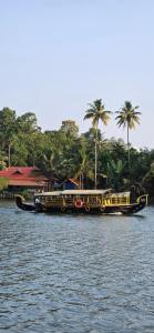 a long boat on the water with palm trees at LemonTree Homestay & Camping in Kollam