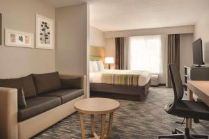 PellaにあるCountry Inn & Suites by Radisson, Pella, IAのソファとベッド付きのホテルルーム