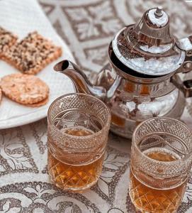 a tea pot and two glasses of tea on a table at The magic of camping in Marrakech