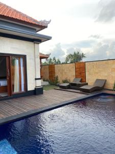 a swimming pool with a wooden deck and a house at Villa Ole in Ubud