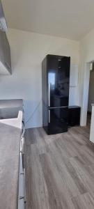 un grande frigorifero nero in una camera con pavimento in legno di Zweibettzimmer "Grau" in zentraler Lage a Brema