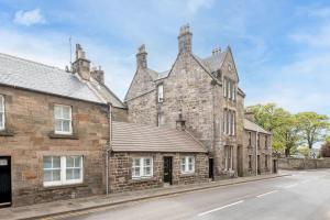 un antiguo edificio de piedra al lado de una calle en The Golf Cottage - 30 Seconds to The Old Course en St Andrews