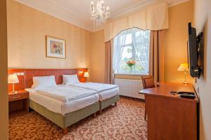 a bedroom with a bed and a desk and a window at Spa Resort PAWLIK-AQUAFORUM in Františkovy Lázně