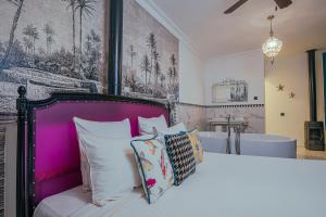 a bedroom with a bed with a purple headboard and a bath tub at Riad Tibibt in Marrakesh