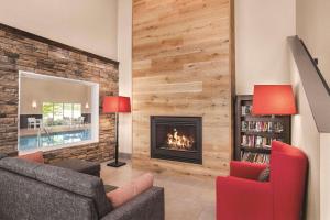 a living room with a fireplace and red chairs at Country Inn & Suites by Radisson, Buffalo, MN in Buffalo
