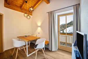 jadalnia ze stołem i krzesłami oraz oknem w obiekcie Mountain Residence Kasern Nr 4 w mieście Predoi