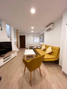 ein Wohnzimmer mit einem gelben Sofa und einem TV in der Unterkunft Villajoyosa Family Apartment in Villajoyosa