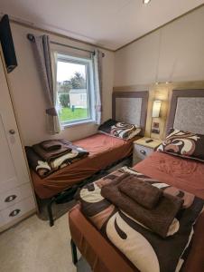a bedroom with two beds and a window at Ambleside SHOREFIELD Holiday Park in Quiet cul de sac ENTERTAINMENT AND LEISURE PASSES INCLUDED in Milford on Sea