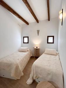 2 Betten in einem Zimmer mit weißen Wänden und Fenstern in der Unterkunft Villajoyosa Family Apartment in Villajoyosa
