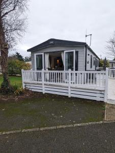 a mobile home with a white fence at Ambleside SHOREFIELD Holiday Park in Quiet cul de sac ENTERTAINMENT AND LEISURE PASSES INCLUDED in Milford on Sea
