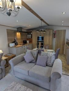 a living room with a couch and a kitchen at Ambleside SHOREFIELD Holiday Park in Quiet cul de sac ENTERTAINMENT AND LEISURE PASSES INCLUDED in Milford on Sea