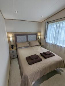 a bedroom with a large bed with two towels on it at Ambleside SHOREFIELD Holiday Park in Quiet cul de sac ENTERTAINMENT AND LEISURE PASSES INCLUDED in Milford on Sea