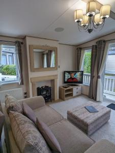 a living room with a couch and a tv at Ambleside SHOREFIELD Holiday Park in Quiet cul de sac ENTERTAINMENT AND LEISURE PASSES INCLUDED in Milford on Sea