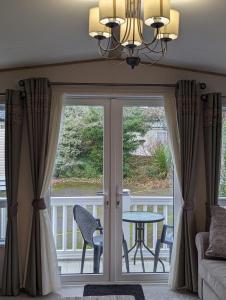 a room with a sliding glass door with a table and chairs at Ambleside SHOREFIELD Holiday Park in Quiet cul de sac ENTERTAINMENT AND LEISURE PASSES INCLUDED in Milford on Sea