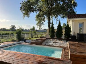 uma piscina num quintal com um deque de madeira em Maison vue sur vignes Piscine chauffée Privée 6per BELLEVUE em Cussac-Fort-Medoc