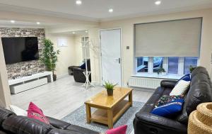 a living room with a leather couch and a tv at Addlestone Stylish Spacious Three Bedroom House in Addlestone