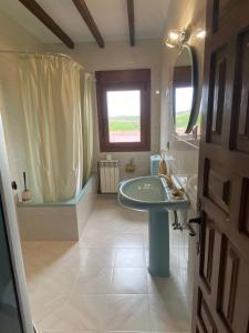 ein Bad mit einem Waschbecken, einem Spiegel und einem Fenster in der Unterkunft Apartamentos La Portilla in El Tejo
