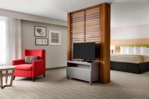 Habitación de hotel con cama, TV y silla roja. en Country Inn & Suites by Radisson, Seattle-Tacoma International Airport, WA en SeaTac