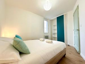 a bedroom with a large white bed with pillows at L'IMPÉRIAL - Jardin & Parking in Mont-de-Marsan