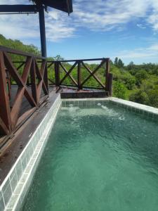 a pool of water with a fence and trees at Cabaña Panambi in Villa Serrana
