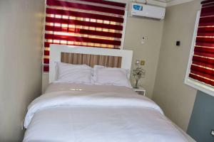 een groot wit bed in een kamer met een raam bij Movomo Limbe in Limbe