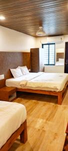 two beds in a room with wooden floors at Baga Sea Link in Baga
