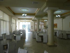 a dining room with white tables and white chairs at Hotel Rossi in Vlorë