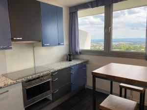 a kitchen with blue cabinets and a table and windows at Skyline Appartement mit Pool and Netflix in Kronberg im Taunus