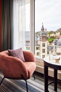 einen Stuhl und einen Tisch in einem Zimmer mit Fenster in der Unterkunft Dorint Hotel Esplanade Jena in Jena