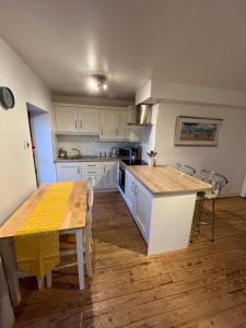 a kitchen with white cabinets and a wooden table at Apartment 12, Sea Wharf in Westport