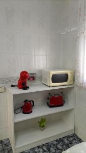 eine Mikrowelle auf einem Regal neben einer Küche in der Unterkunft Casa Quico in Higuera de Arjona